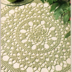 May include: A green crocheted doily with a delicate floral pattern. The doily is round and has a center with a smaller floral design.