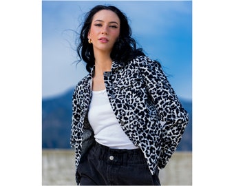 May include: A black and white leopard print denim jacket with a white tank top and black pants.