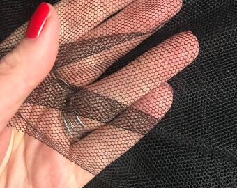 Peut inclure: Tulle noir avec un motif en maille fine. Le tissu est tenu dans une main, montrant sa texture délicate.