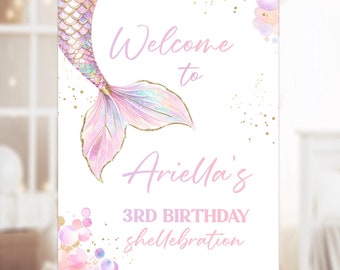May include: A welcome sign for a 3rd birthday party with a mermaid tail graphic. The sign is white with pink and gold accents and says "Welcome to Ariella's 3rd Birthday Shellebration".
