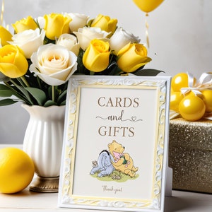 Pu&ograve; includere: Un cartello bianco incorniciato con un bordo giallo e un'illustrazione di Winnie the Pooh e Maialino. Il cartello recita "Cartoline e Regali" con un simbolo di cuore e "Grazie!" in fondo. Il cartello &egrave; su un tavolo bianco con un bouquet di rose gialle e bianche in un vaso bianco e palloncini gialli sullo sfondo.