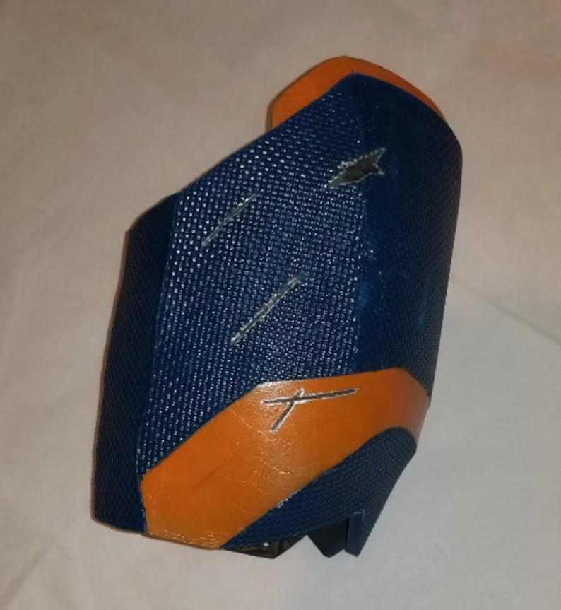 May include: A blue and orange protective arm guard with a textured surface.