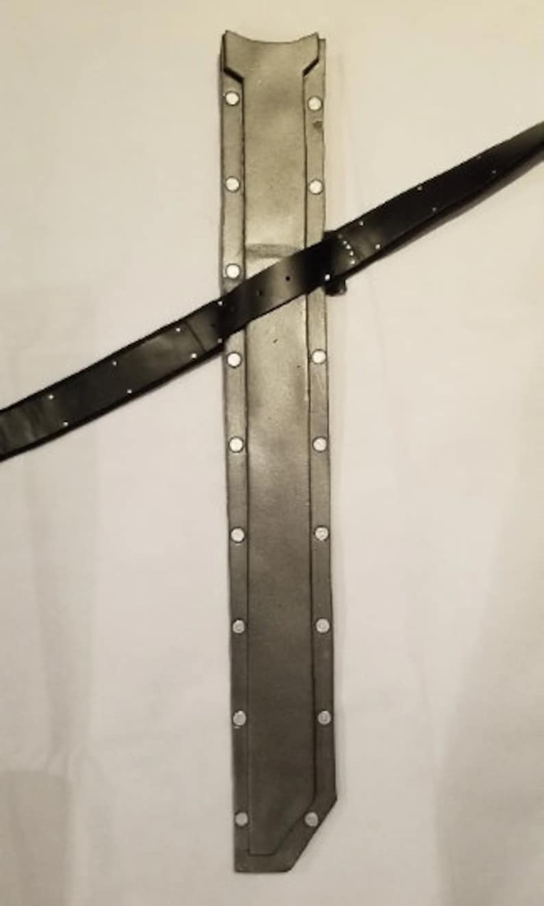 May include: A grey leather scabbard with a black leather strap. The scabbard has a pointed tip and a rounded top. The strap is attached to the scabbard with metal rivets.