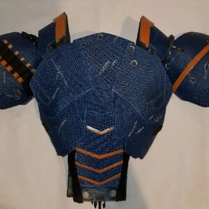 May include: Blue and orange costume armour piece with a textured fabric surface.
