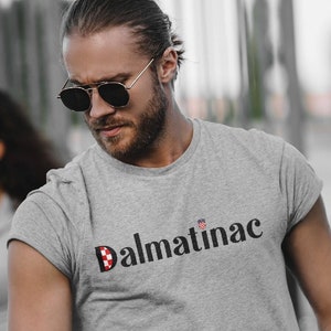 Könnte beinhalten: Ein graues T-Shirt mit einem schwarz-weiß karierten Logo, auf dem "Dalmatinac" steht.