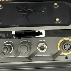 May include: Black electronic device with multiple connection ports labeled Power, Speed, Temp, NMEA 2000, NMEA 0183 (x2), Ethernet, and Sonar-Temp. The device has a hummingbird logo and is likely for marine use.