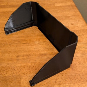 May include: A black plastic screen shade for a computer monitor. The shade is designed to block out glare and improve visibility.