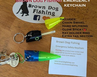 May include: Emergency keychain from Brown Dog Fishing. The keychain includes a chain swivel, hard split ring, glow stick, key holder ring, and extra tail section. The keychain is black, blue, and green. The text on the keychain says "Brown Dog Fishing Emergency Keychain."