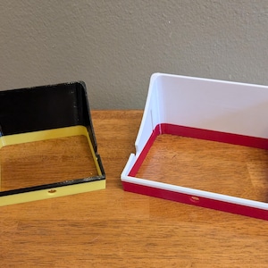 Here is a side by side comparison of the two sizes of the GoPro sunshade.  On the left in black and yellow for this example, is the standard sized shade.  On the right in white and red is the media sized shade.  You can see that the media sized shade is wider and taller to accommodate easy setup with the popular Media mod.