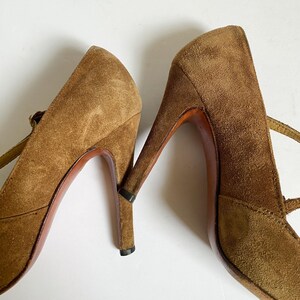 May include: A pair of brown suede high-heeled shoes with ankle straps. The shoes have a pointed toe and a stiletto heel.