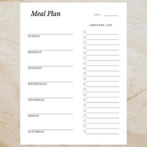 May include: A white meal plan sheet with the words "Meal Plan" at the top. The sheet includes sections for each day of the week and a grocery list with check boxes. The background is a light beige marble.