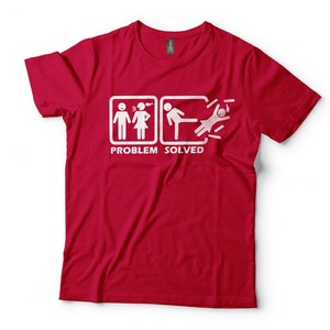 Puede incluir: Camiseta roja con un gr&aacute;fico blanco de dos figuras de palo discutiendo, seguido de una figura de palo pateando a otra figura de palo. El texto "PROBLEM SOLVED" est&aacute; debajo del gr&aacute;fico.