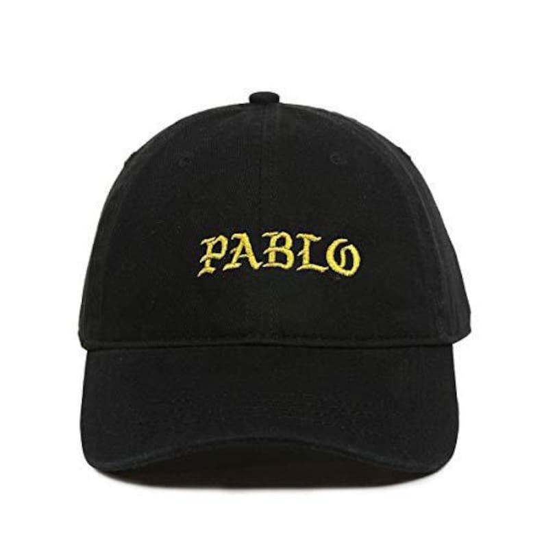 Puede incluir: Gorra de b&eacute;isbol negra con la palabra "PABLO" bordada en hilo dorado en la parte delantera. La gorra tiene una visera curva y un peque&ntilde;o bot&oacute;n en la parte superior.