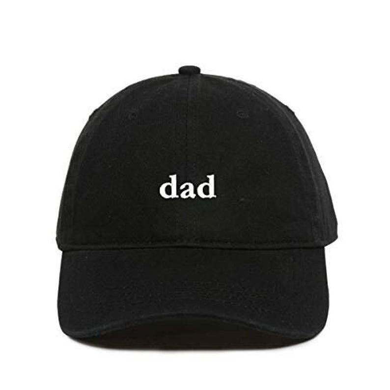 Op de afbeelding: Zwarte baseballcap met het witte woord "dad" geborduurd op de voorkant. De cap heeft een gebogen klep en een kleine knoop bovenop. Een casual accessoire.