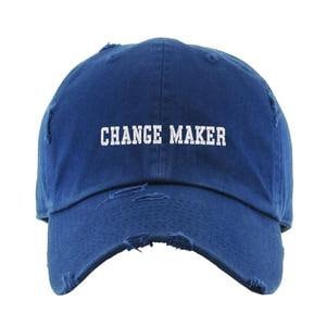 May include: A blue distressed baseball cap with white embroidered text that reads "CHANGE MAKER".