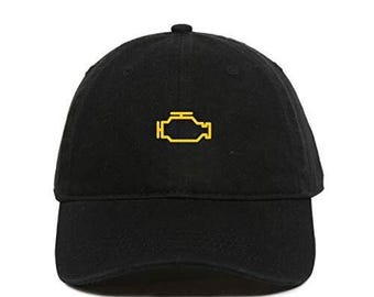 May include: Black baseball cap with a yellow engine light symbol embroidered on the front. The cap has a curved brim and a button on top. A classic, adjustable hat.