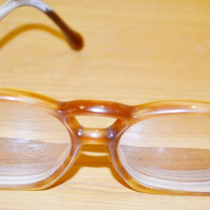 May include: A pair of brown tortoiseshell eyeglasses with round lenses. The glasses have a simple, classic design.