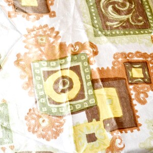 Könnte beinhalten: Nahaufnahme eines Stoffes mit einem sich wiederholenden Muster aus Quadraten und floralen Formen. Die Quadrate sind in Braun-, Grün- und Gelbtönen gehalten, mit einem weißen Hintergrund. Die floralen Formen sind in Braun- und Orangetönen gehalten.