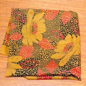 May include: A yellow and black patterned scarf with red and orange floral designs.