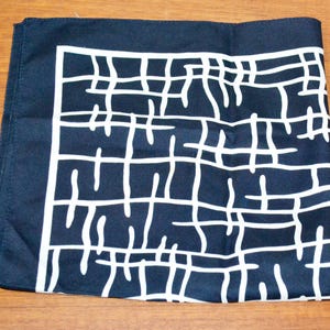 Könnte beinhalten: Ein gefaltetes quadratisches, marineblaues Tuch mit weißem Gittermuster. Das Tuch aus weichem Stoff eignet sich als Halstuch oder Einstecktuch. Maße: ca. 40 cm x 40 cm.