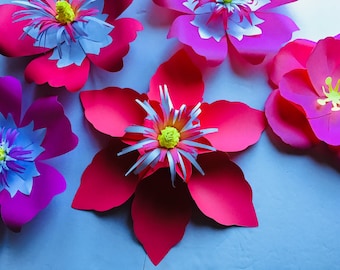 May include: Five paper flowers in shades of pink and red with white centers. The flowers are layered on a light blue background.