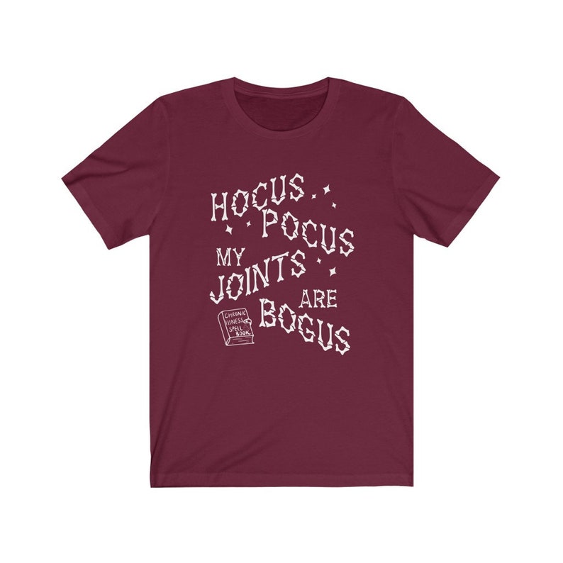 May include: Burgundy t-shirt with white text that reads "Hocus Pocus My Joints Are Bogus" and a small image of a book that says "Chronic Haxing Spell Book".