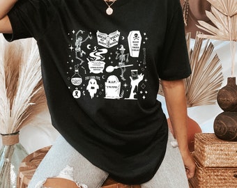 May include: Black t-shirt with a white graphic print of a cauldron, skeletons, and other Halloween-themed imagery. The text on the graphic includes "Focus My Body Focus My Pogus", "Unsolicited Advice", "You Look Fine", "R.I.P. I'm Fine", "Cures", and "Have You Tried Yoga?"