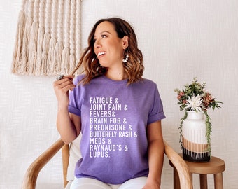 Może przedstawiać: Fioletowy T-shirt z białym tekstem, który brzmi "FATIGUE & JOINT PAIN & FEVERS & BRAIN FOG & PREDNISONE & BUTTERFLY RASH & MEDS & RAYNAUD'S & LUPUS."