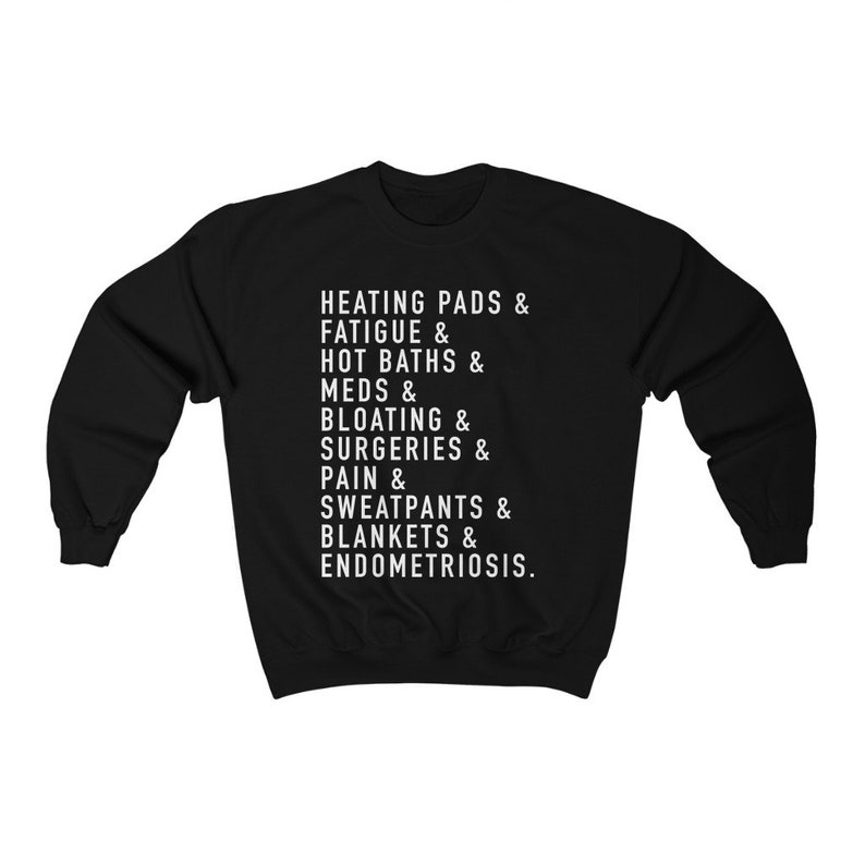 May include: Black sweatshirt with white text that reads "HEATING PADS & FATIGUE & HOT BATHS & MEDS & BLOATING & SURGERIES & PAIN & SWEATPANTS & BLANKETS & ENDOMETRIOSIS."
