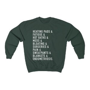 May include: A dark green sweatshirt with white text that reads "HEATING PADS & FATIGUE & HOT BATHS & MEDS & BLOATING & SURGERIES & PAIN & SWEATPANTS & BLANKETS & ENDOMETRIOSIS."