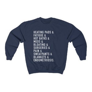 May include: Navy blue sweatshirt with white text that reads "HEATING PADS & FATIGUE & HOT BATHS & MEDS & BLOATING & SURGERIES & PAIN & SWEATPANTS & BLANKETS & ENDOMETRIOSIS."