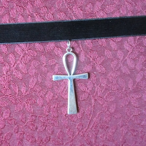 May include: A black velvet choker necklace with a silver ankh pendant.
