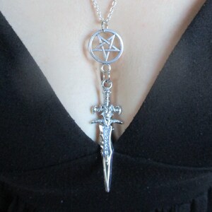 May include: A silver necklace with a pentagram pendant and a sword charm.