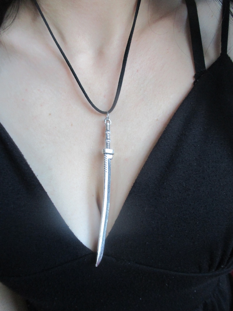 May include: A silver sword pendant on a black cord necklace.