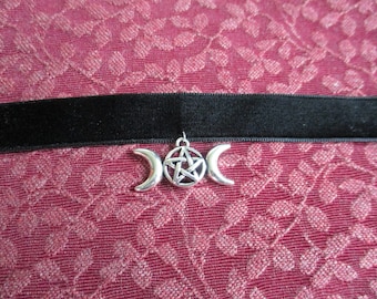 May include: Black velvet choker with a silver pendant featuring a triple moon and pentagram design.