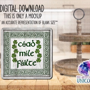 May include: A digital download mockup featuring a wooden sign with the text "céad míle fáilte" in green, surrounded by shamrocks and Celtic knot designs. The sign is on a wooden surface, with a two-tiered wooden tray and a unicorn sticker in the background.