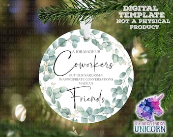 Op de afbeelding: Een witte ronde ornament met een groen eucalyptusbladeren ontwerp. De ornament heeft de tekst "A job made us coworkers but our sarcasm & inappropriate conversations made us friends".