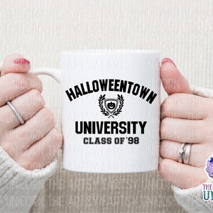 May include: White ceramic mug with a black graphic that says "Halloweentown University Class of '98". The graphic includes a black and white illustration of a pumpkin with a wreath around it.