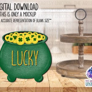 May include: Green pot with gold coins and the word "LUCKY" in gold glitter letters. The pot is sitting on a wooden tiered tray.