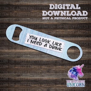May include: A blue bottle opener with a white label that says "You look like I need a drink". The bottle opener is on a wooden background.
