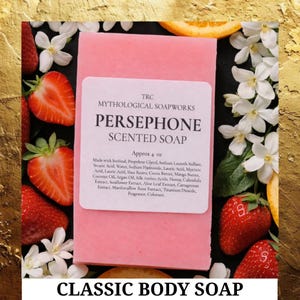 May include: A pink Persephone scented soap bar from Mythological Soapworks, approximately 4 oz, with a white label. The soap is surrounded by fresh strawberries, white flowers, and orange slices. The words "CLASSIC BODY SOAP" are at the bottom.