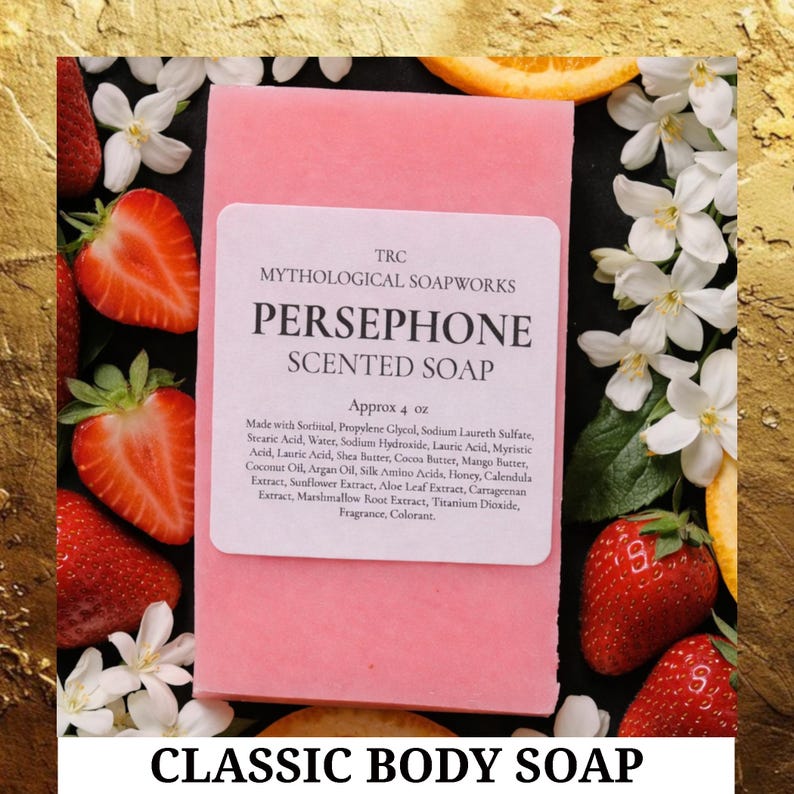 May include: A pink Persephone scented soap bar from Mythological Soapworks, approximately 4 oz, with a white label. The soap is surrounded by fresh strawberries, white flowers, and orange slices. The words "CLASSIC BODY SOAP" are at the bottom.