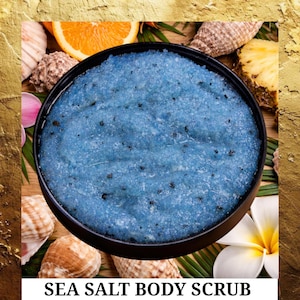 May include: A round black container filled with blue sea salt body scrub. The scrub is surrounded by seashells, a slice of orange, a piece of pineapple, and a white flower. The text "SEA SALT BODY SCRUB" is at the bottom.