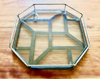 May include: Octagonal glass tray with a silver metal frame. The tray has a geometric pattern on the bottom.