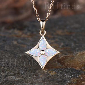 May include: A rose gold necklace featuring a four-pointed star-shaped pendant with four marquise-cut iridescent white opals arranged in a floral pattern. The pendant hangs from a delicate rose gold chain. The text RHfinds is visible in the image.