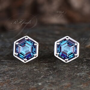 May include: A pair of silver stud earrings with a hexagonal blue gemstone in each. The gemstones have a faceted cut and sparkle.