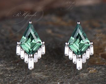 May include: A pair of silver earrings with a green gemstone in the center and a fringe of smaller diamonds around the stone.