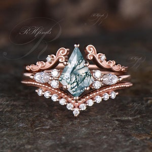 Pode incluir: Conjunto de aliança de noivado em ouro rosa com uma pedra central de ágata musgosa e um design delicado e ornamentado. A aliança apresenta uma ágata musgosa única de forma triangular com um padrão verde e branco. A banda é adornada com pequenos diamantes brilhantes.