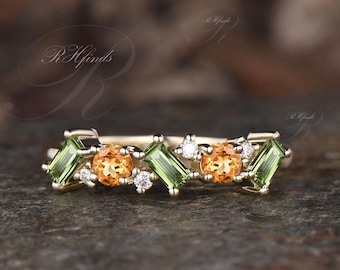 May include: A gold band ring with a row of alternating green and orange gemstones, and small clear diamonds.