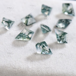 May include: A collection of ten moss agate gemstones, each cut into a diamond shape. The stones are translucent and have a variety of green and white patterns.